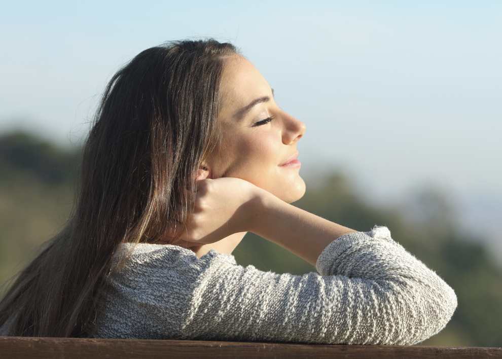 Photo of woman relaxing with sun on her face.