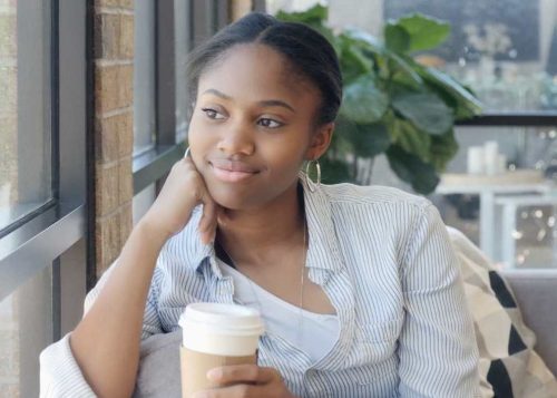 Young woman dreaming of her future, looking out of café window.